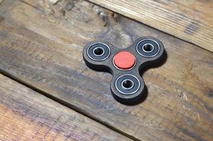 A rare handmade wooden fidget spinner lies on a brown wooden background surface. Trendy stress relieving toy photo