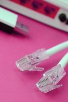 Internet router, portable USB wi-fi adapter and internet cable plugs lie on a bright pink background. Items required for internet photo