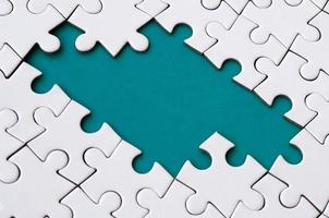 Close-up texture of a white jigsaw puzzle in assembled state with missing elements forming a blue pad for text. Copy space photo