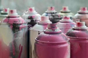 A lot of dirty and used aerosol cans of bright pink paint. Macro photograph with shallow depth of field. Selective focus on the spray nozzle photo