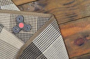 A rare wooden handmade spinner lies on a checkered plaid on a brown wooden background surface. Trendy stress relieving toy photo