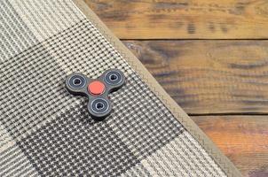 A rare wooden handmade spinner lies on a checkered plaid on a brown wooden background surface. Trendy stress relieving toy photo