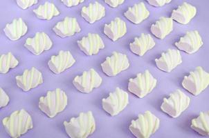 Colorful marshmallow laid out on violet paper background. pastel creative textured pattern. Perspective macro shot photo