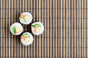 Sushi rolls lies on a bamboo straw serwing mat. Traditional Asian food. Top view. Flat lay minimalism shot with copy space photo