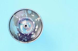 lata de aerosol usada con gotas de pintura azul sobre fondo de textura de papel de color azul pastel de moda foto