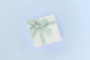 Small white gift box with ribbon lies on a violet background photo