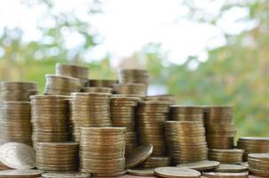 Big amount of shiny ukrainian old 1 hryvnia coin stacks close up on wooden table on green trees backdrop. The concept of business and rich life in Ukraine photo