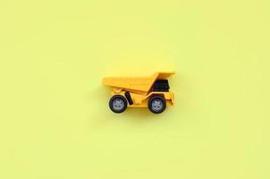 Small yellow toy truck on texture background of fashion pastel yellow color paper in minimal concept photo