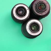 Several photographic lenses lie on a bright turquoise background. Copy space photo