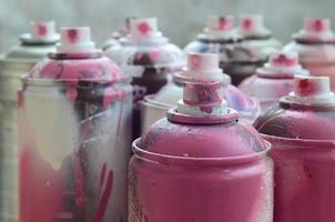 A lot of dirty and used aerosol cans of bright pink paint. Macro photograph with shallow depth of field. Selective focus on the spray nozzle photo