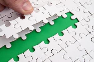 The human hand paves the way to the surface of the jigsaw puzzle, forming a green space. The concept of overcoming the difficulties on the way to success photo
