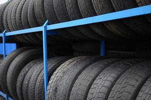Rack with variety of car tires in automobile store. Many black tires. Tire stack background. Selective focus photo