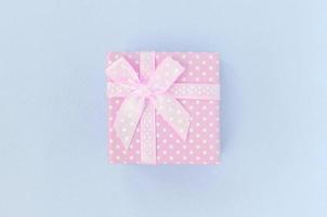 Small pink gift box with ribbon lies on a violet background photo