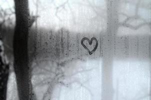 The heart is painted on the misted glass in winter photo