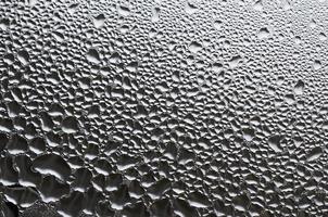 A photo of the glass surface of the window, covered with a multitude of droplets of various sizes. Background texture of a dense layer of condensate on glass