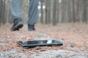 Young man loses his smartphone on Russian autumn fir wood path. Carelessness and losing expensive mobile device concept photo