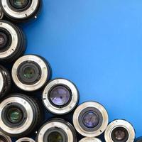 Several photographic lenses lie on a bright blue background. Space for text photo