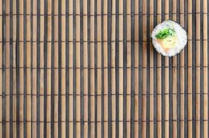 Sushi roll lie on a bamboo straw serwing mat. Traditional Asian food. Top view. Flat lay minimalism shot with copy space photo