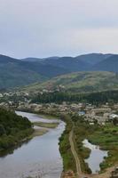 A beautiful view of the village of Mezhgorye, Carpathian region. A lot of residential buildings surrounded by high forest mountains and long river photo