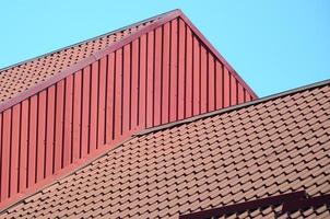 A fragment of a roof from a metal tile of dark red color. Quality Roofing photo