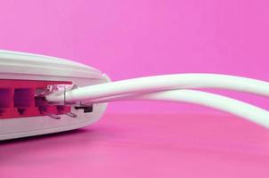 The Internet cable plugs are connected to the Internet router, which lies on a bright pink background. Items required for Internet photo