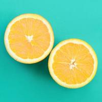 Top view of a several orange fruit slices on bright background in turquoise green color. A saturated citrus texture image photo
