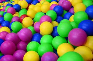 muchas bolas de plástico de colores en una piscina para niños en un parque infantil. patrón de primer plano foto