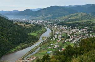 una hermosa vista del pueblo de mezhgorye, región de los cárpatos. muchos edificios residenciales rodeados de montañas altas y ríos largos foto