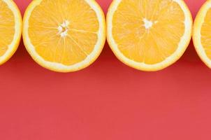 Top view of a several orange fruit slices on bright background in red color. A saturated citrus texture image photo