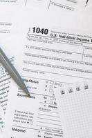 el bolígrafo y el cuaderno se encuentran en el formulario de impuestos 1040 us declaración de impuestos sobre la renta individual. la hora de pagar impuestos foto