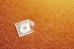 The background texture of a large pile of buckwheat, in the middle of which you see a bill of one US dollar. The concept of higher prices for cereals photo