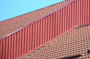 A fragment of a roof from a metal tile of dark red color. Quality Roofing photo