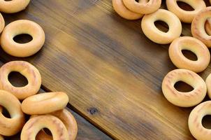 A lot of fresh yellow bagels lie on the surface of the old dark wood. A popular kind of flour products. One of the traditional Russian treats for tea photo