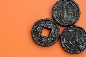 Three chocolate products in the form of Euro, USA and Japan coins lie on an orange plastic background. A model of cash coins in an edible form photo