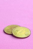 Two golden bitcoins lies on a blanket made of soft and fluffy light pink fleece fabric. Physical visualization of virtual crypto currency photo