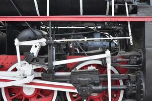 ruedas de la vieja locomotora de vapor negra de la época soviética. el lado de la locomotora con elementos de la tecnología giratoria de trenes antiguos foto