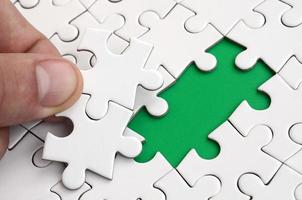 The human hand fills the last missing elements of the surface from the jigsaw puzzle. The concept of the completion of the initiated cases photo