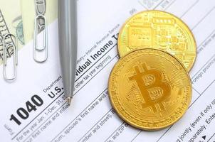 el bolígrafo, los bitcoins y los billetes de dólar se encuentran en el formulario de impuestos 1040 de la declaración de impuestos sobre la renta de las personas físicas. la hora de pagar impuestos foto