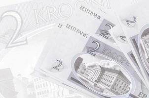 2 billetes de coronas estonias se encuentran apilados sobre el fondo de un gran billete semitransparente. presentación abstracta de la moneda nacional foto