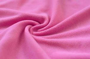 The blanket of furry pink fleece fabric. A background of light pink soft plush fleece material with a lot of relief folds photo