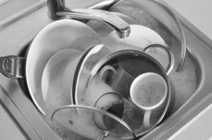 Dirty dishes and unwashed kitchen appliances filled kitchen sink photo