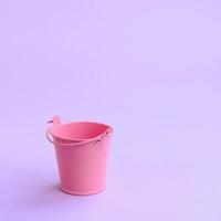 un cubo rosa vacío en miniatura se encuentra sobre un fondo violeta pastel. concepto mínimo foto