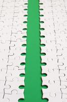 The green path is laid on the platform of a white folded jigsaw puzzle. Texture image with copy space for text photo