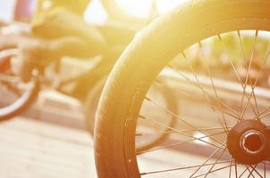 A BMX bike wheel against the backdrop of a blurred street with cycling riders. Extreme Sports Concept photo