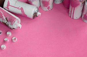 Some used pink aerosol spray cans and nozzles with paint drips lies on a blanket of soft and furry light pink fleece fabric. Classic female design color. Graffiti hooliganism concept photo