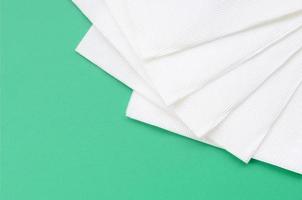 Several white paper napkins lie on a plastic green background photo