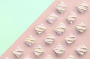 Colorful marshmallow laid out on turquoise and pink paper background photo