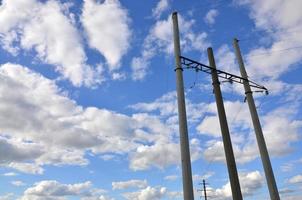 Concrete pole with wires of power line against the background of blue cloudy sky photo