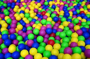 muchas bolas de plástico de colores en una piscina para niños en un parque infantil. patrón de primer plano foto