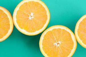 Top view of a several orange fruit slices on bright background in turquoise green color. A saturated citrus texture image photo